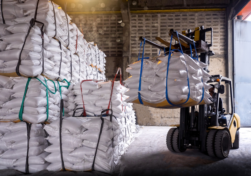 Chariot élévateur transportant des sacs de sucre conditionnés en vrac dans un entrepôt logistique